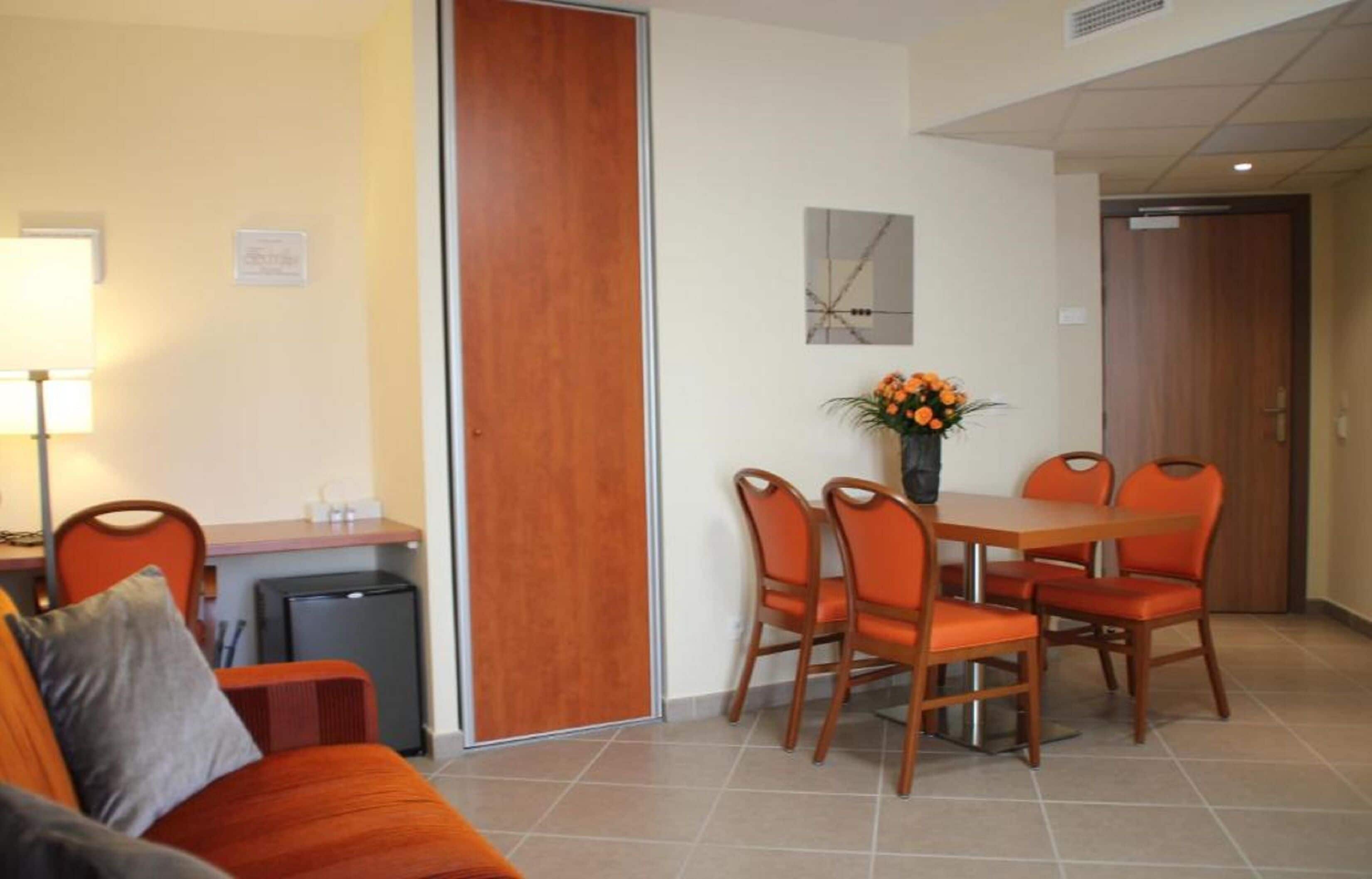 A compact living space with a dining area, a sofa, a small table, and a lamp.
