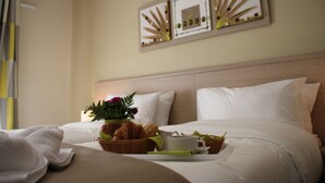 A neatly made bed with white linens, a basket of croissants, a cup of coffee, and a small vase of flowers on the bedside table. - The Originals Boutique, Hôtel l'Occitan, Aubagne Nord (La Destrousse)