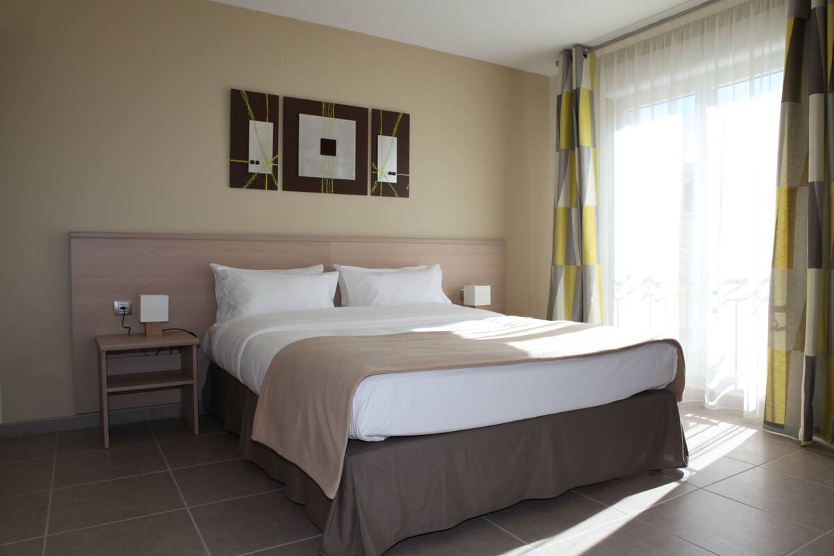 A hotel room with a bed, bedside tables, and artwork on the wall.