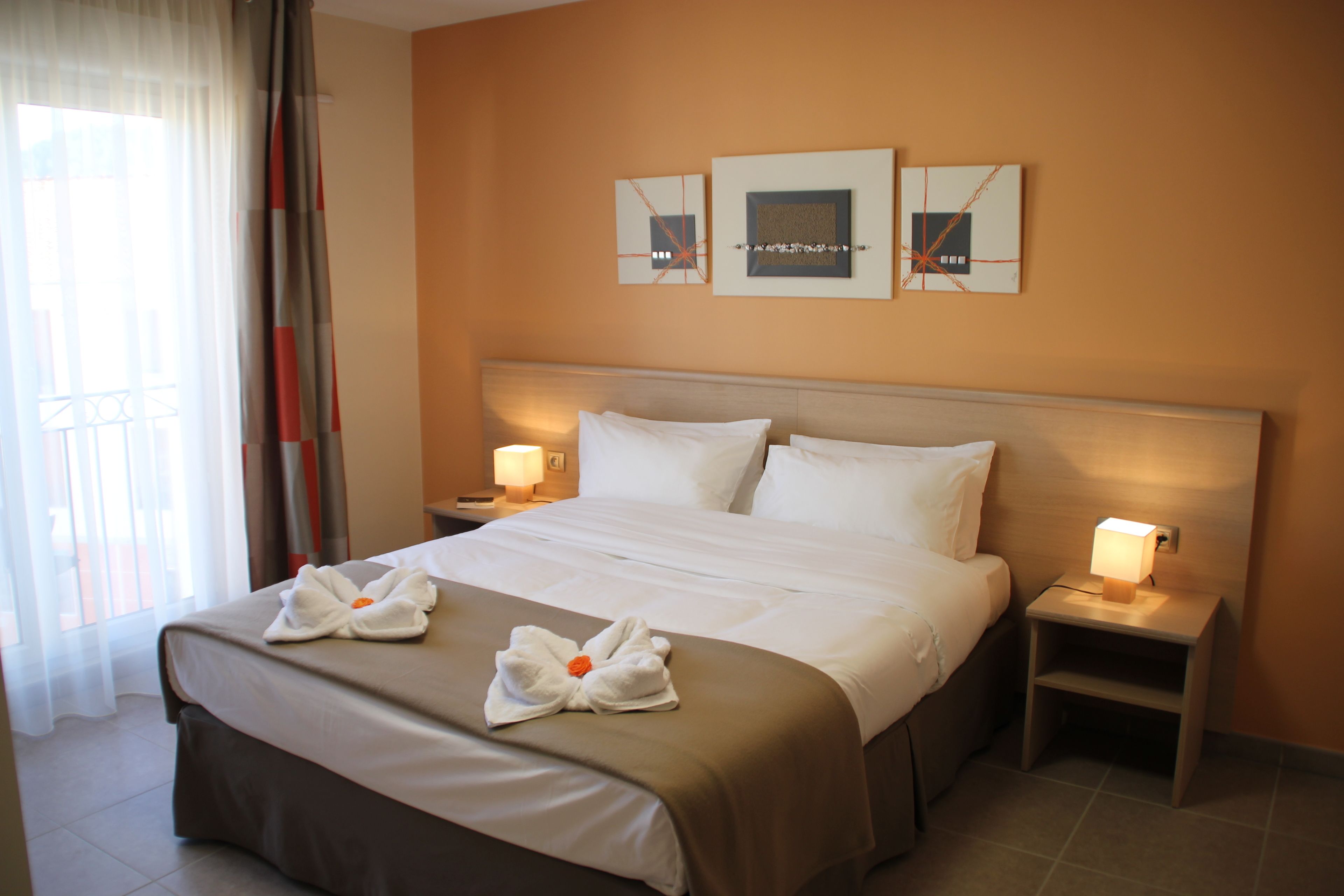 Una habitación de hotel con una cama grande, dos mesitas de noche con lámparas y una obra de arte en la pared.