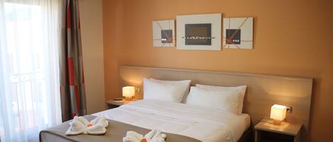A hotel room with a large bed, two bedside tables with lamps, and artwork on the wall.
