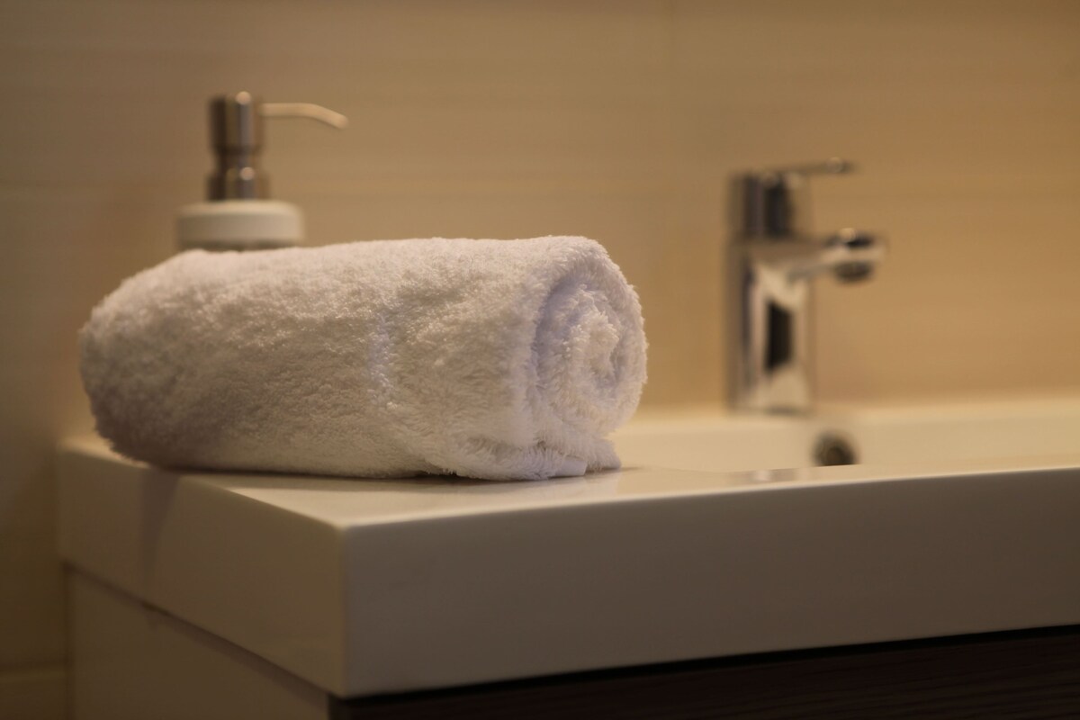 A white towel on a bathroom sink with a faucet and a soap dispenser.