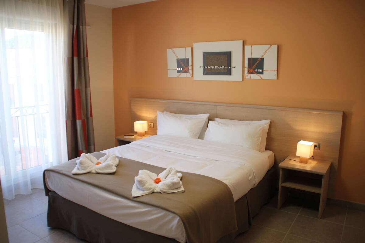 A hotel room with a large bed, two bedside tables with lamps, and artwork on the wall.