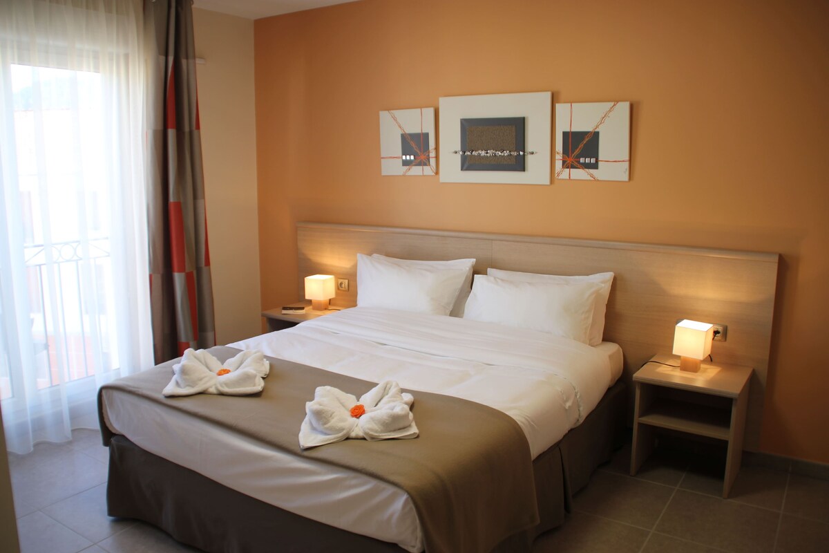 A hotel room with a large bed, two bedside tables with lamps, and artwork on the wall.