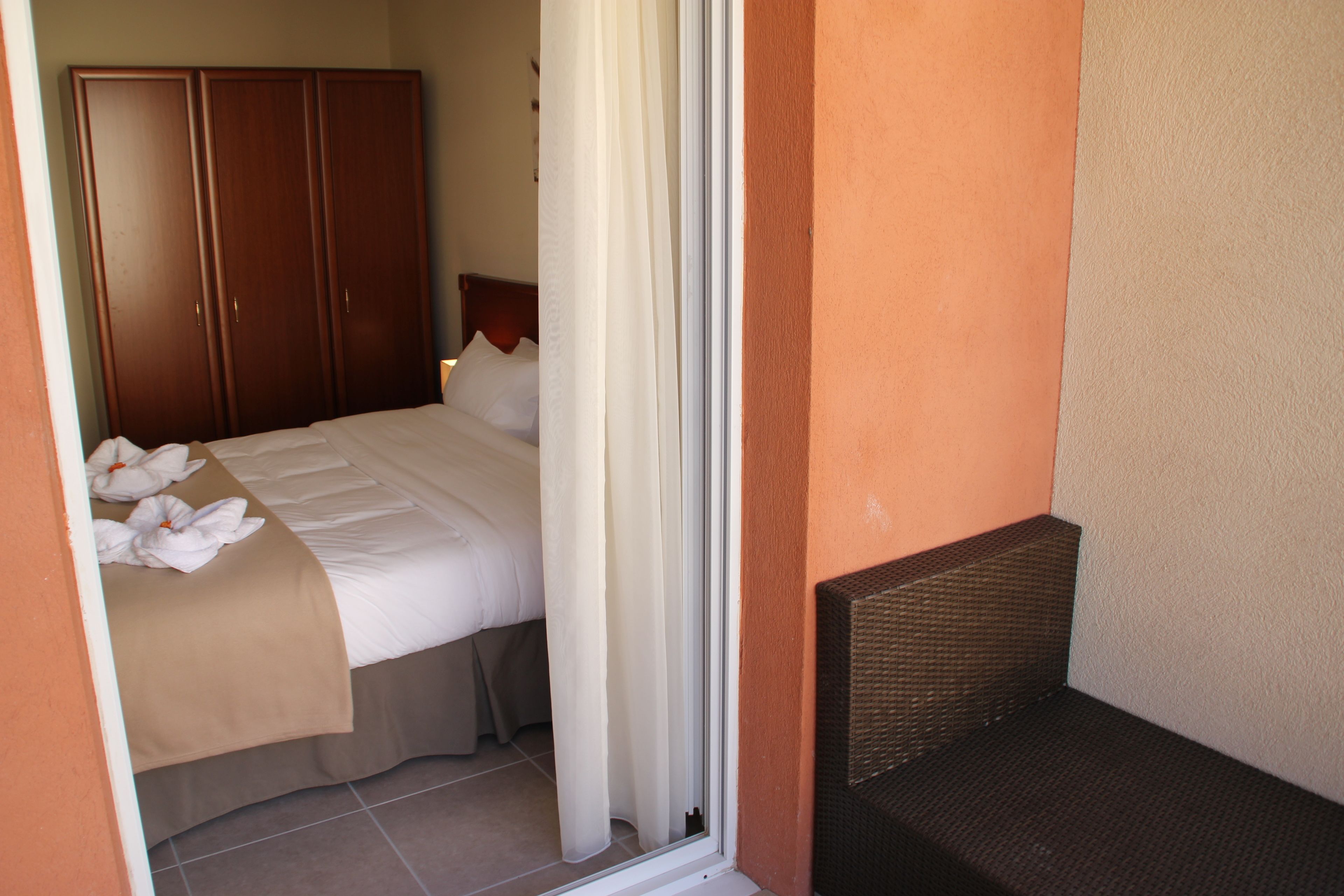 A hotel room with a bed, a wardrobe, and a small seating area.