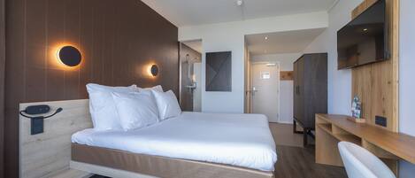 Una habitación de hotel moderna con una cama grande, un escritorio y un televisor montado en la pared.
