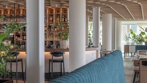 Un área de bar moderna con mostrador, taburetes y una variedad de botellas y vasos.