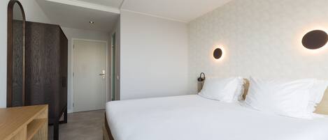 A bedroom with a large bed, a wooden desk, and a wardrobe.