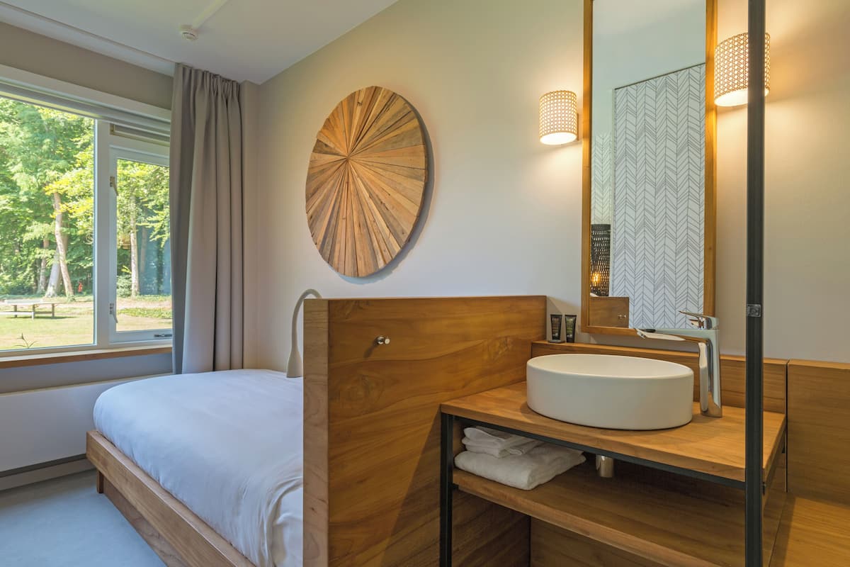 A modern bedroom with a wooden headboard, a round mirror, and a built-in sink.