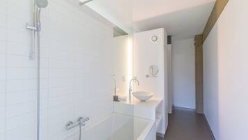 Une salle de bain moderne avec une douche à parois de verre, un lavabo blanc et un miroir.