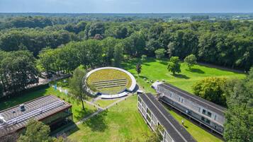 Ein Luftbild eines Campus mit einem kreisförmigen Gebäude, umgeben von grünen Rasenflächen und Bäumen.