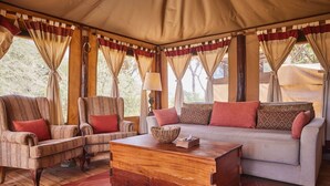 A cozy room with a sofa, two armchairs, a wooden coffee table, and a patterned rug. - Elephant Bedroom Camp (Samburu)