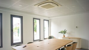 Un salón de conferencias con una mesa larga, seis sillas y ventanas amplias.