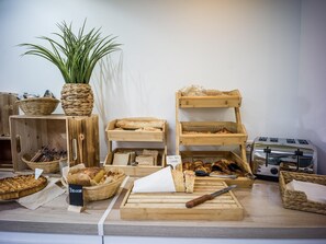 Een bakkerijdisplay met diverse broden, gebakjes en een bordje met de tekst 'Pão Troço Cereais'.