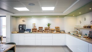 A modern cafe with a coffee machine, a tea station, and various food items on display. - BRIT HOTEL CONFORT ROISSY SAINT-WITZ (Saint-Witz)