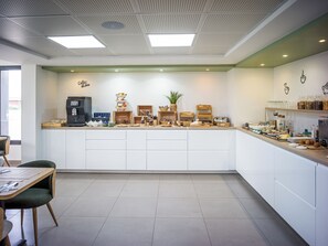 A modern cafe with a coffee machine, a tea station, and various food items on display. - BRIT HOTEL CONFORT ROISSY SAINT-WITZ (Saint-Witz)