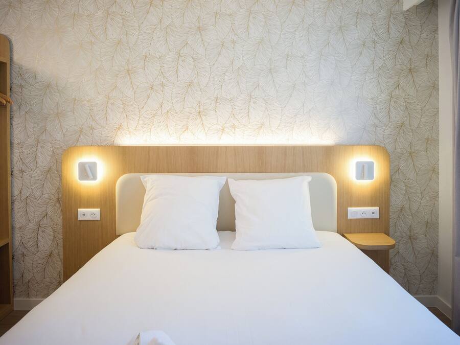 Una habitación de hotel con una cama grande, dos mesitas de noche y una pared con diseño de hojas.