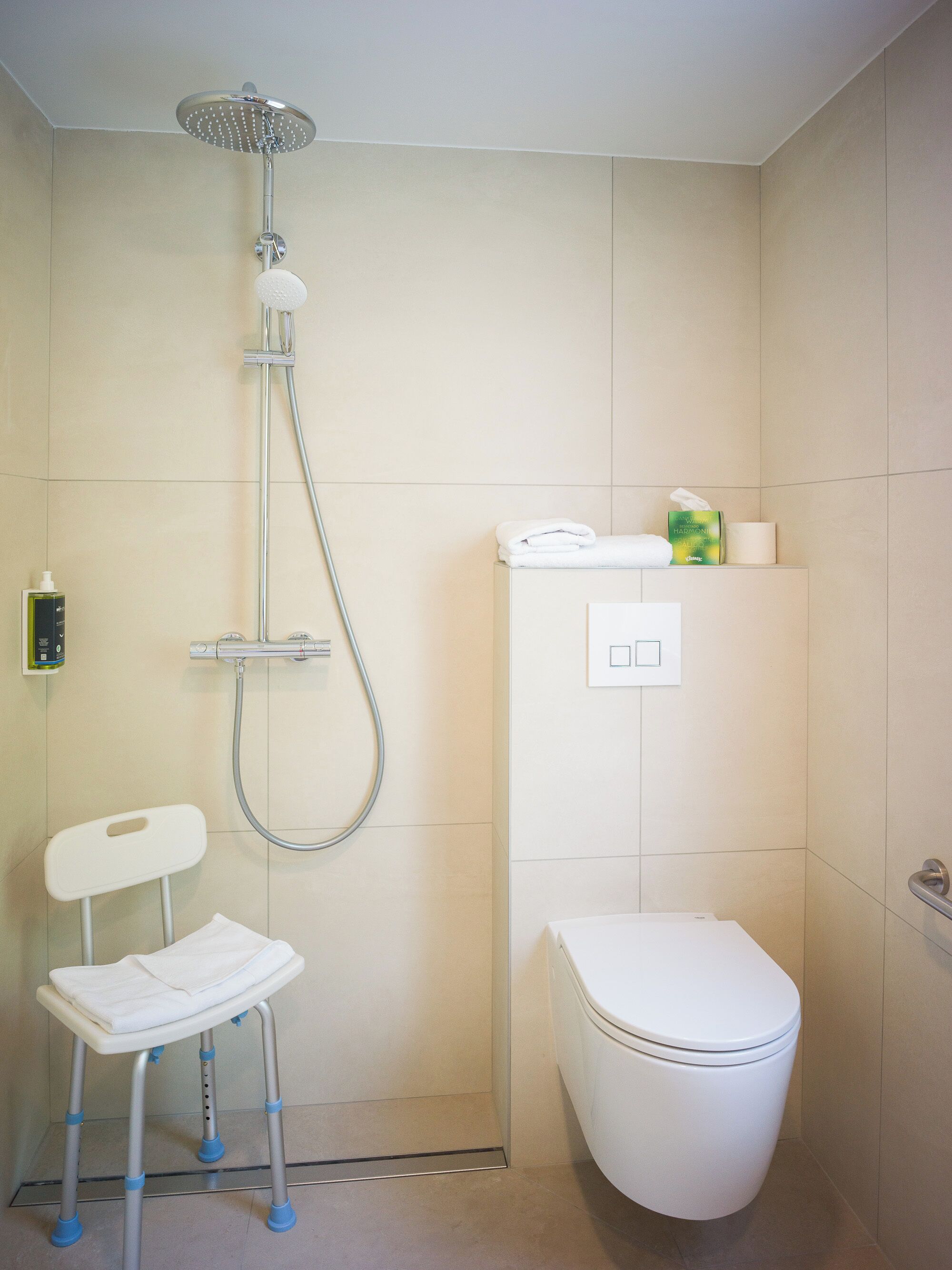 Ein Badezimmer mit Dusche, Toilette und einem kleinen Stuhl.