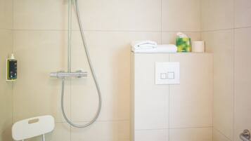 Ein Badezimmer mit Dusche, Toilette und einem kleinen Stuhl.