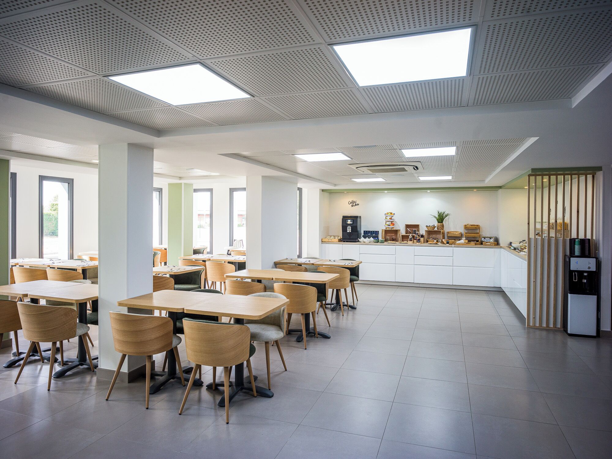 A modern dining area with tables and chairs, a coffee station, and a view of the outdoors.