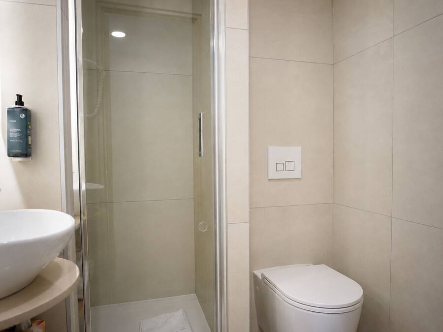 A bathroom with a glass-enclosed shower, a toilet, and a sink.