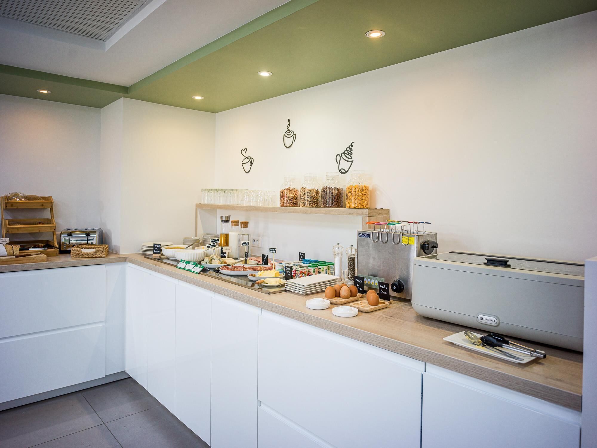 A modern kitchen with a breakfast bar, various food items, and a coffee machine.