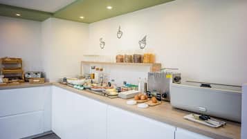 Una cocina moderna con barra de desayuno, diversos alimentos y una cafetera.