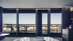 A hotel room with a large window, a bed with towels, a chair, and a desk. - Hotel Mercure Cherbourg Centre Port (Cherbourg-en-Cotentin)