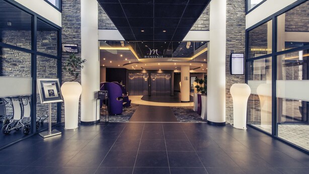 A modern lobby with a reception desk, elevators, and a glass wall. - Hotel Mercure Cherbourg Centre Port (Cherbourg-en-Cotentin)