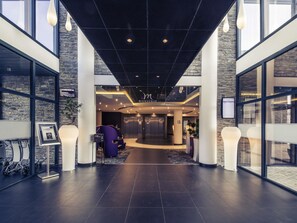 A modern lobby with a reception desk, elevators, and a glass wall. - Hotel Mercure Cherbourg Centre Port (Cherbourg-en-Cotentin)