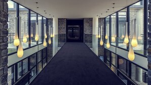 A corridor with large windows, hanging pendant lights, and stone walls. - Hotel Mercure Cherbourg Centre Port (Cherbourg-en-Cotentin)