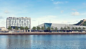 A modern hotel with a glass facade, located beside a body of water. - Hotel Mercure Cherbourg Centre Port (Cherbourg-en-Cotentin)