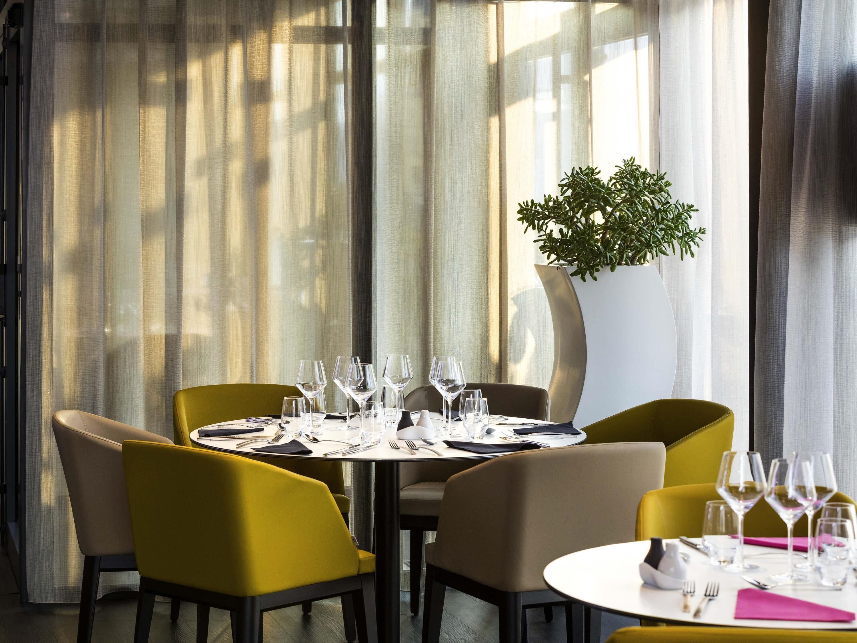 A dining area with a table set for four, surrounded by chairs, and a large potted plant.