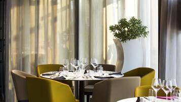 A dining area with a table set for four, surrounded by chairs, and a large potted plant.