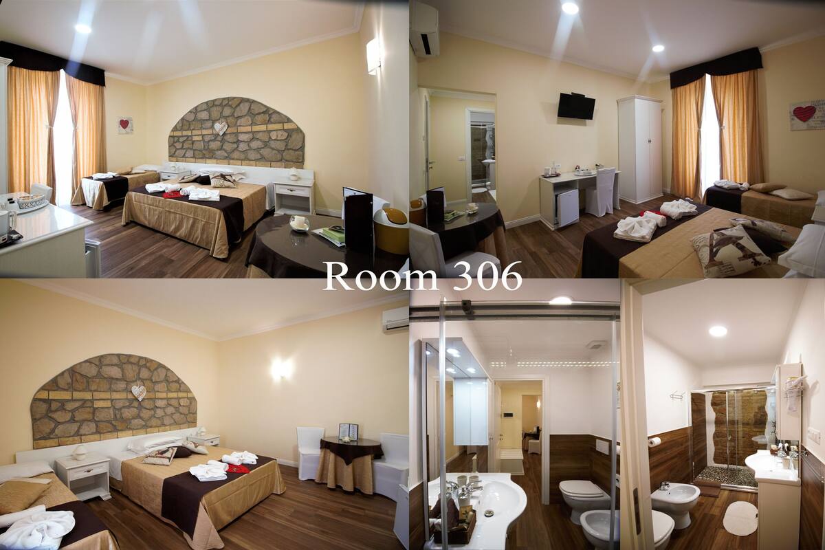 A hotel room with a stone fireplace, a dining area, a bathroom with a shower, and a separate toilet.