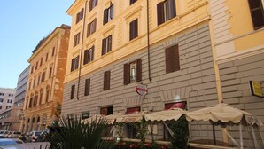 A multi-story building with a yellow facade, multiple windows, and a street-level restaurant with outdoor seating. - Freedom Love B&B (Rome)