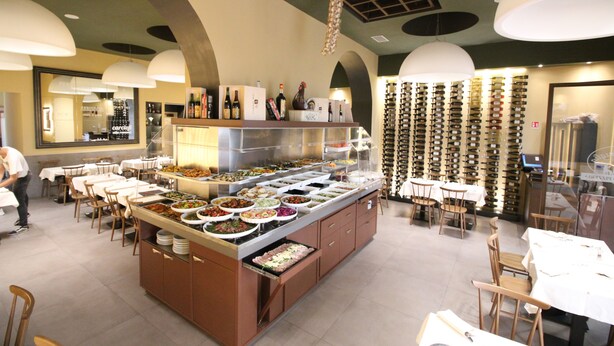 A buffet area with multiple food stations, a wine rack, and a seating area with tables and chairs. - Freedom Love B&B (Rome)