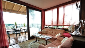 A living room with a sofa, coffee table, and dining area with chairs and a table. - Felline In B&B (Alliste)