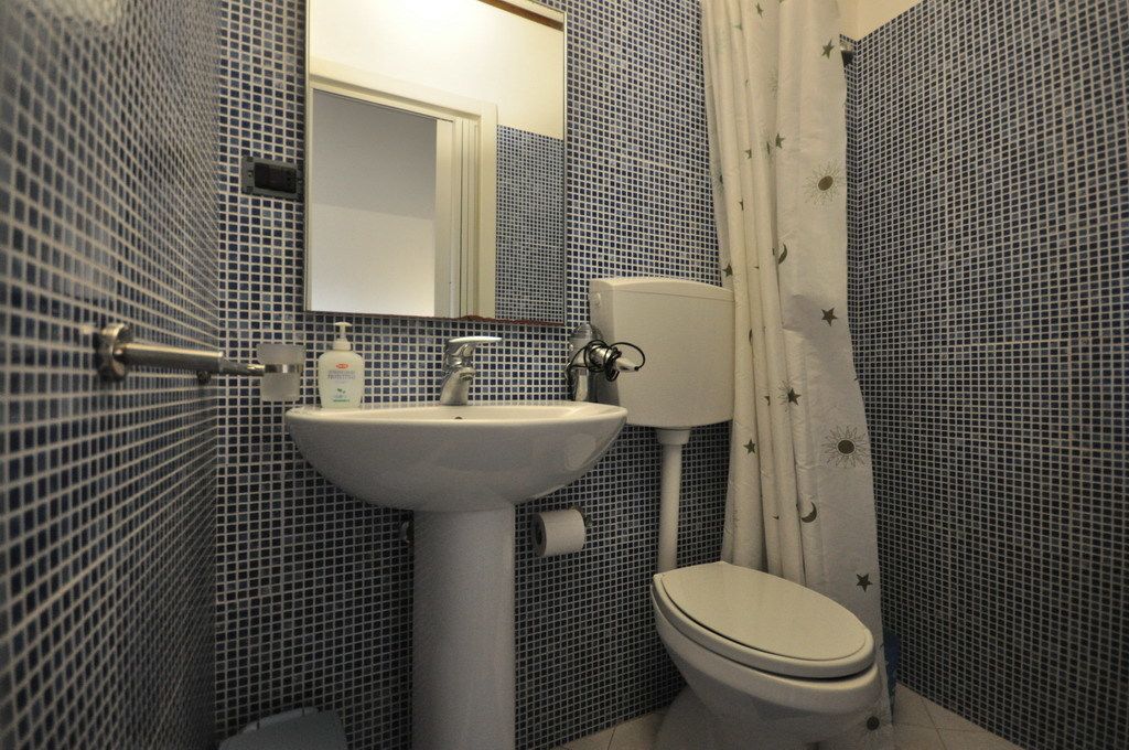 A bathroom with a white sink, toilet, and a mirror above the sink.