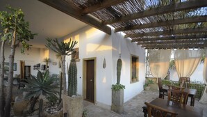 A covered patio with stone flooring, wooden furniture, and various cacti and succulents. - Felline In B&B (Alliste)
