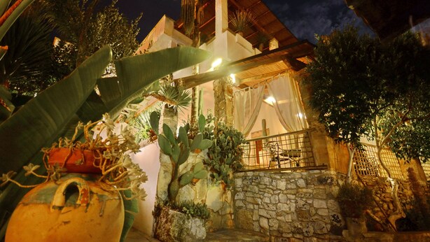 A stone-walled building with a balcony, surrounded by tropical plants and a night sky. - Felline In B&B (Alliste)