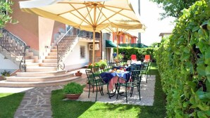Eine Terrasse mit Sitzgelegenheiten im Freien, einer Treppe und einem Hecken.
