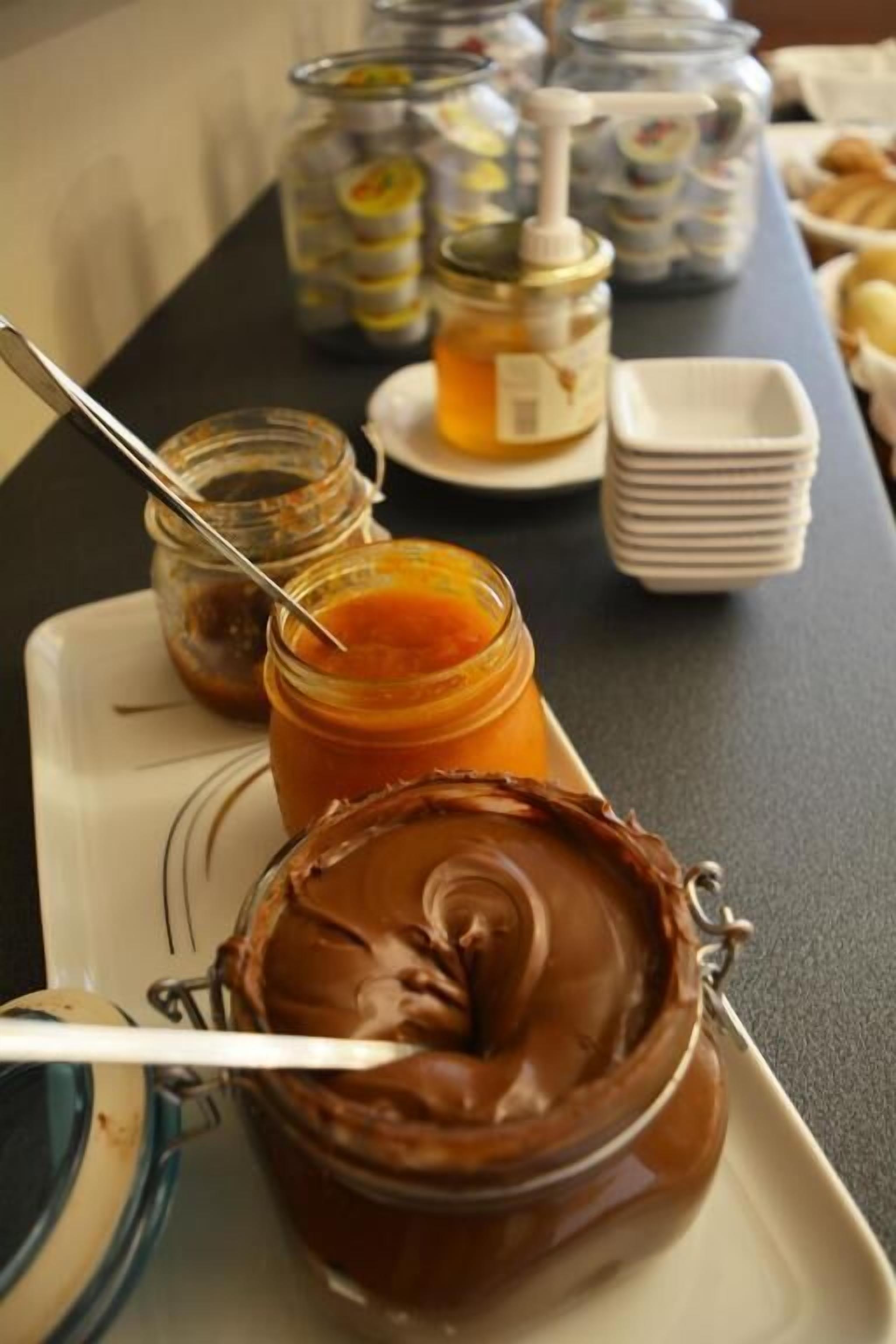 A table with jars of spreads and condiments, including chocolate spread and honey.