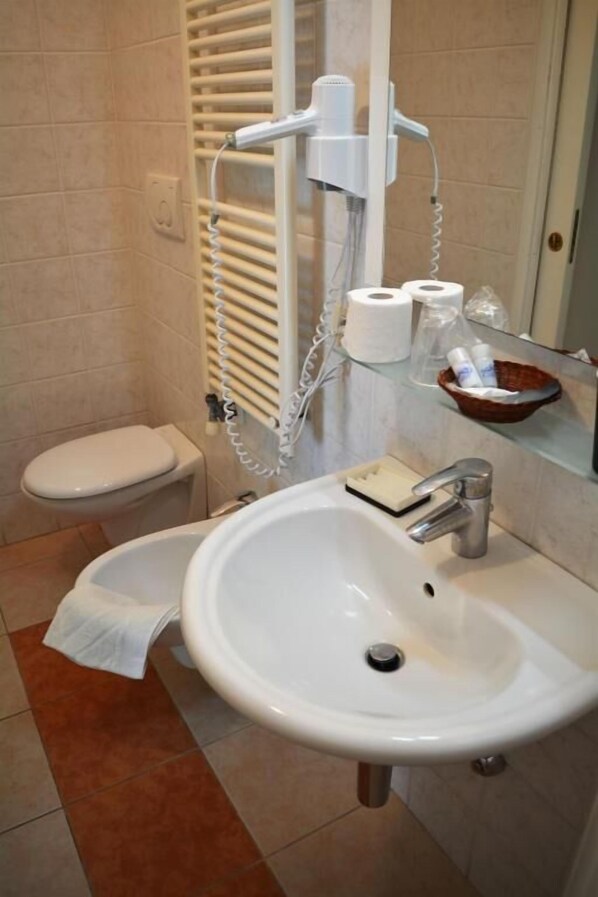Un baño con lavamanos, inodoro y toallero blancos.