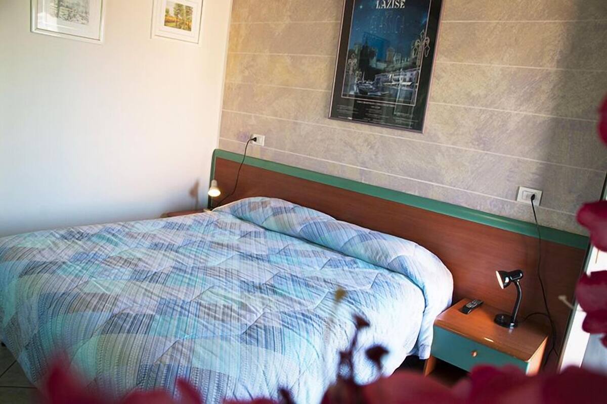 A bedroom with a bed, a nightstand, a lamp, and a poster on the wall.