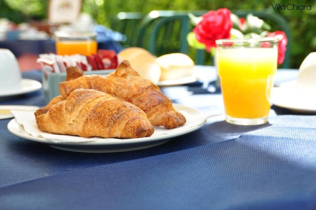 A breakfast setting with croissants and a glass of orange juice on a table.