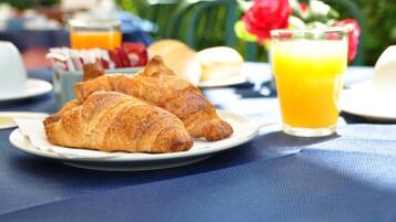 A breakfast setting with croissants and a glass of orange juice on a table.