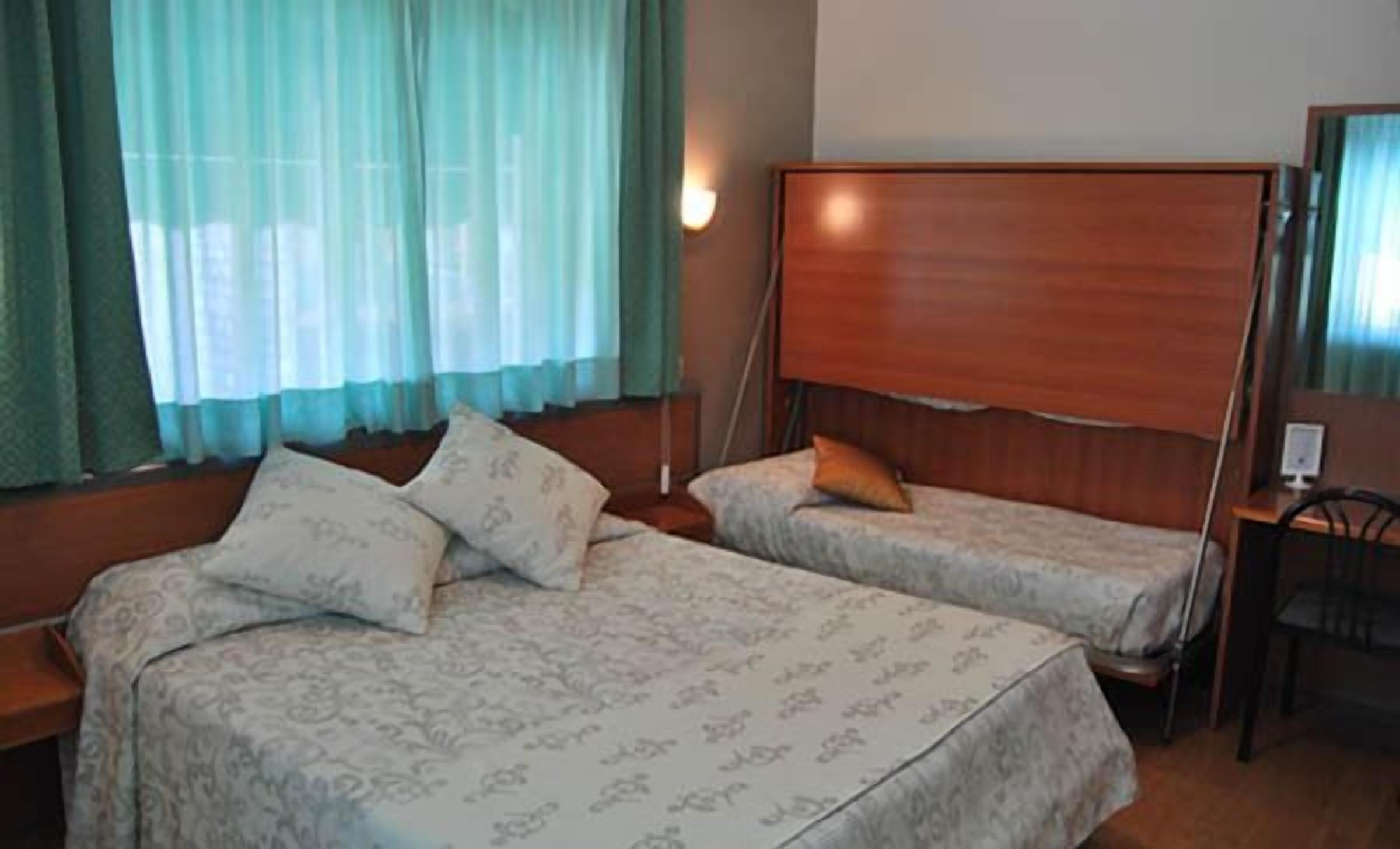 A room with two beds, a desk, and a chair.