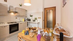 A modern kitchen with a wooden table set for breakfast, featuring various food items and a coffee machine. - Claudia House Roma Termini (Rome)