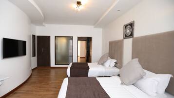 A hotel room with two beds, a flat-screen TV, a large mirror, and a sliding door leading to a bathroom.